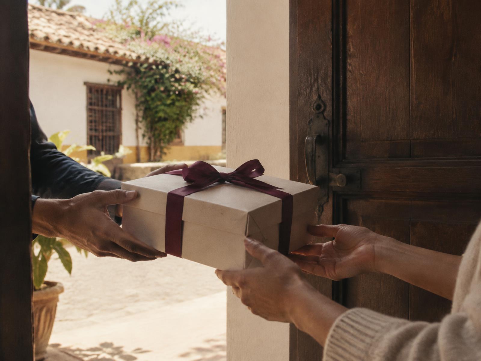 Manos recibiendo una caja LAN en la puerta de una casa